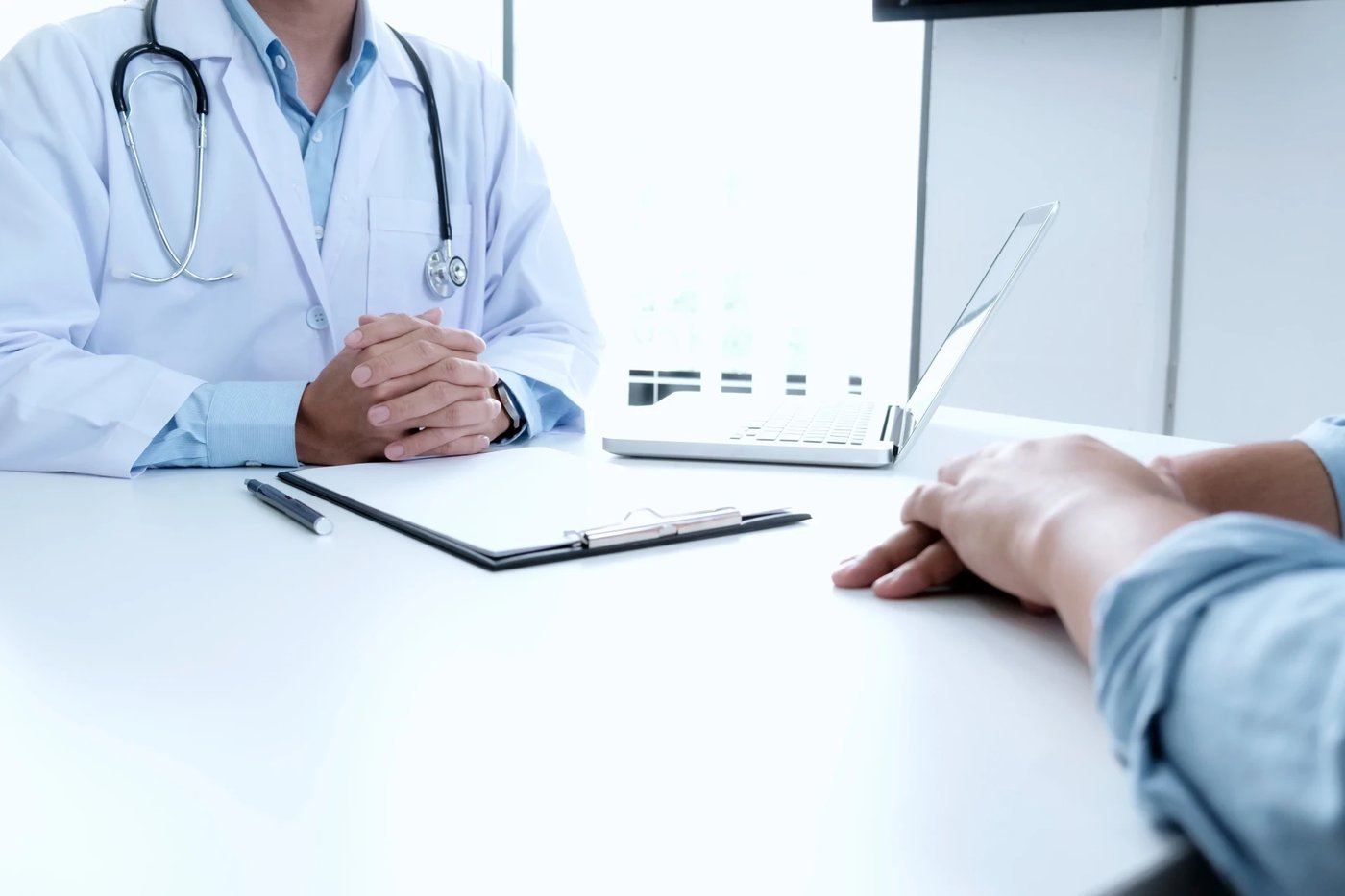 Médico em consulta, à mesa, com o paciente